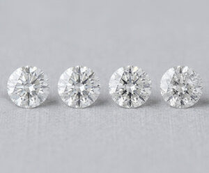 four 1-carat diamonds places in a row and displayed on a grey surface